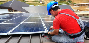 man checking solar panels on a roof