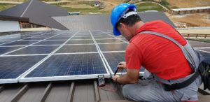 man checking solar panels on a roof