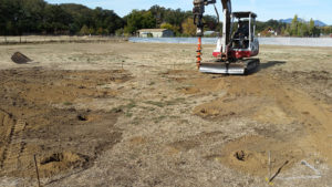 a backhoe with a screw bit digging holes