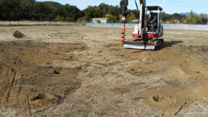 a backhoe with a screw bit digging holes