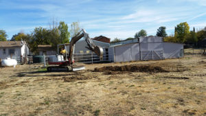 a backhoe digging with house in the background