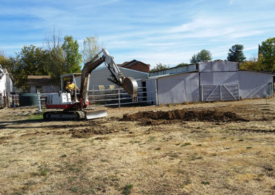 a backhoe digging with house in the background