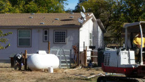 the back end of a backhoe with house in the background