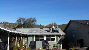 several men on top of a house installing solar panels