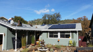 several men on top of a house installing solar panels