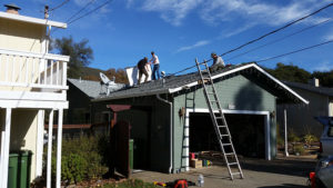 several men on top of a house installing solar panels