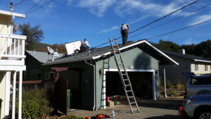 several men on top of a house installing solar panels